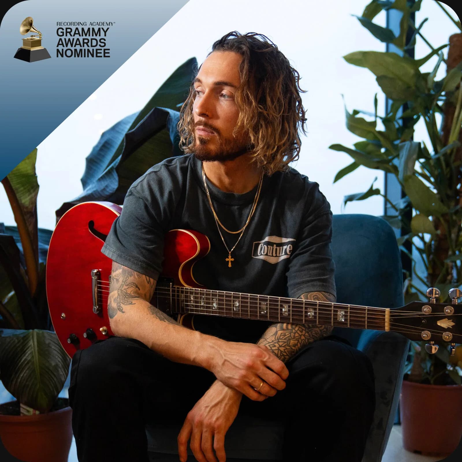 Ashton Sellars seated with a red electric guitar