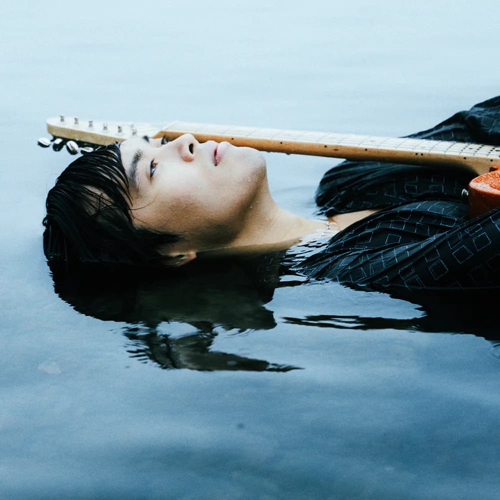 Carlo Redl floating in water with a guitar