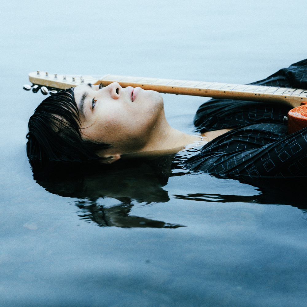 Carlo Redl floating in water with a guitar
